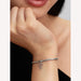 Silver bracelet with a red heart charm on a wrist, close-up view.