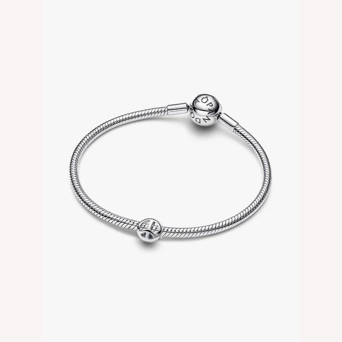 Silver bracelet with a peace symbol charm on a light background