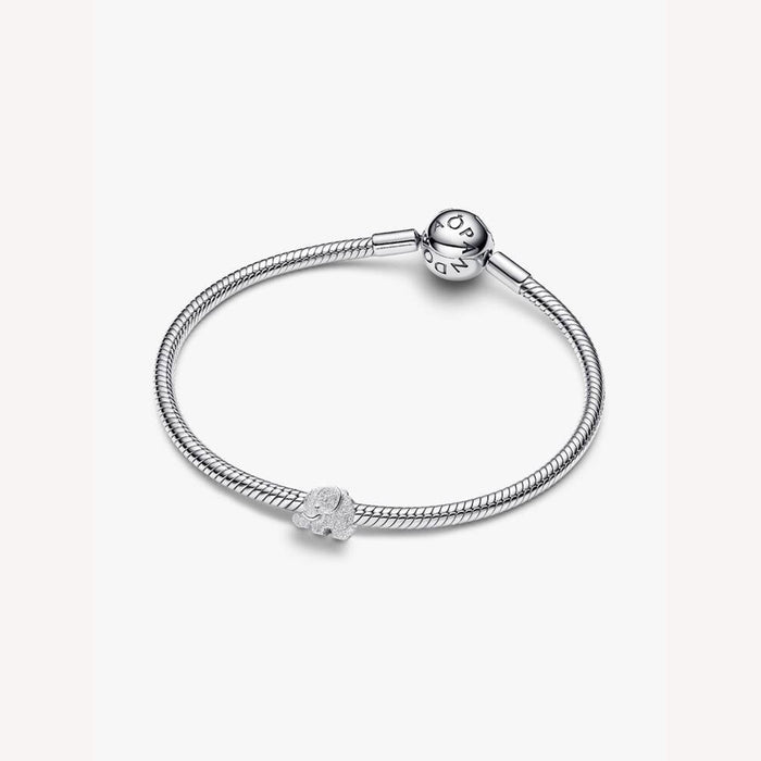 Silver bracelet with a heart-shaped charm on a light pink background