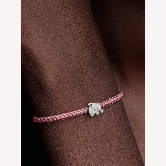 Pink braided bracelet with a silver elephant charm on a wrist 