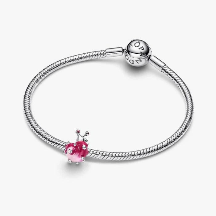 Silver bracelet with a pink heart charm on a white background