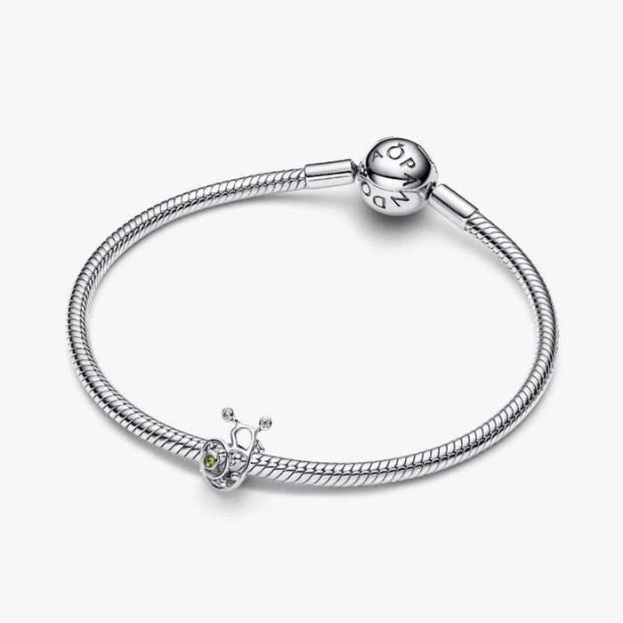 A silver snail charm adorned with green enamel, highlighting its whimsical design and polished surface.