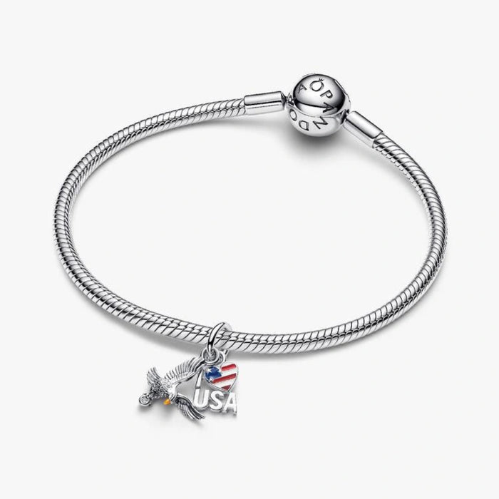 Sterling silver-tone dangle charm featuring a detailed eagle, an American flag heart with red, white, and blue enamel, and a sparkling crystal accent for charm bracelets and necklaces.