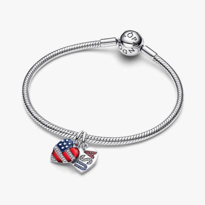 Sterling silver-tone dangle charm set featuring an American flag heart and a white heart with sparkling USA lettering in red, white, and blue crystals, designed for charm bracelets