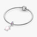 A woman showcases a silver bracelet adorned with a pink turtle charm on her wrist.