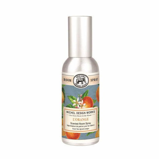 Silver spray bottle labeled "L'Orange Scented Room Spray" by Michel Design Works, with illustrations of oranges and leaves, conveying a fresh scent.