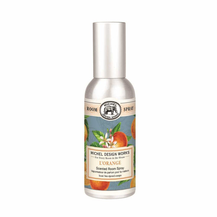 Silver spray bottle labeled "L'Orange Scented Room Spray" by Michel Design Works, with illustrations of oranges and leaves, conveying a fresh scent.