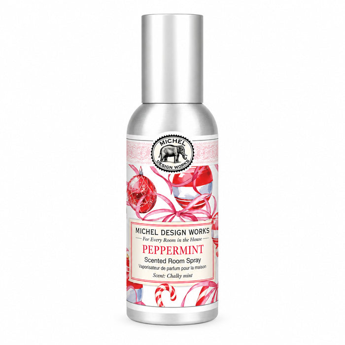 Michel Design Works Peppermint scented room spray in a silver bottle with a tall silver cap and a festive label featuring red ornaments, striped candy canes, and pink ribbon.