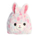 A stuffed bunny with pink and blue spots, featuring floppy ears and a cheerful expression.