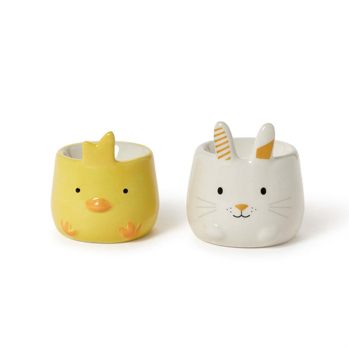 Two decorative ceramic eggs showcase a bunny and a chick inside, highlighting a charming springtime theme.