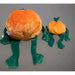 Plush toy resembling a frog with an orange body on a gray background