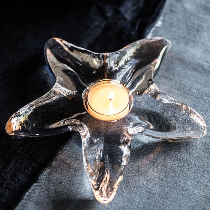 A lit candle placed on a blue table, casting a warm glow in the surrounding area.