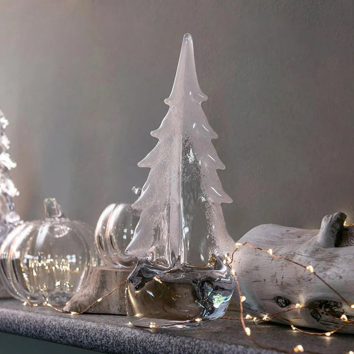 Simon Pearce Vermont Snowy Branches glass evergreen with frosted white branches, displayed beside glass pumpkins and lights