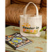 Tote bag with 'Reader in Training' text on a table next to a book