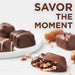 Chocolate-covered treats with nuts on a white surface, accompanied by the text 'SAVOR THE MOMENT'.