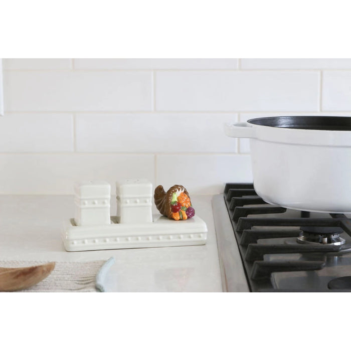 White pot on a stove with a decorative item and salt and pepper shakers in the background.