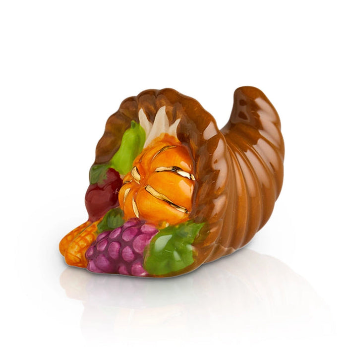 Cornucopia figurine filled with fruits and vegetables on a white background