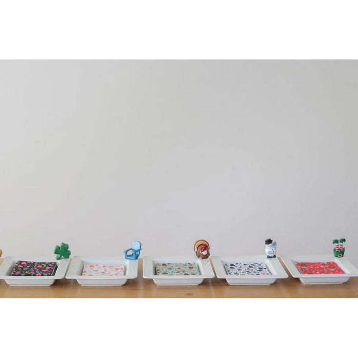 Row of small white containers with colorful patterns on a light gray background