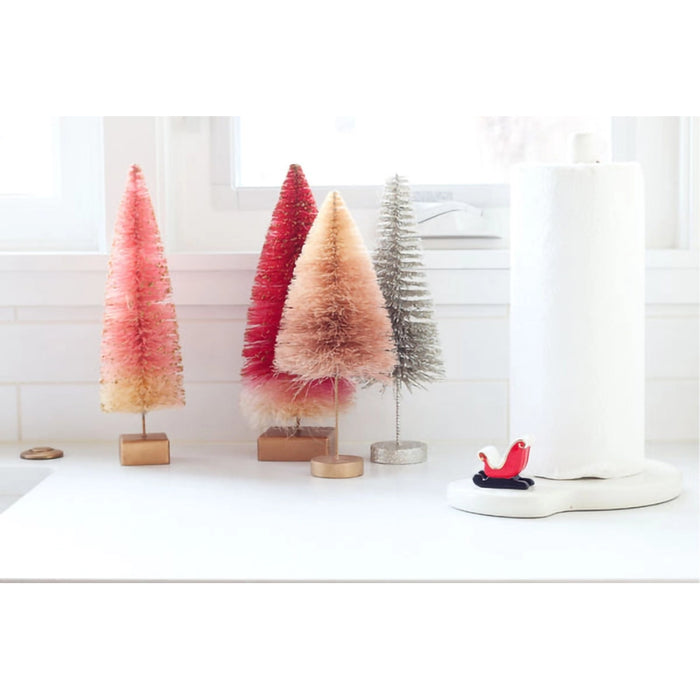 Set of colorful bottlebrush trees on a white surface with a neutral background