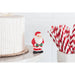 Small Santa Claus figurine next to red and white striped straws on a white surface.