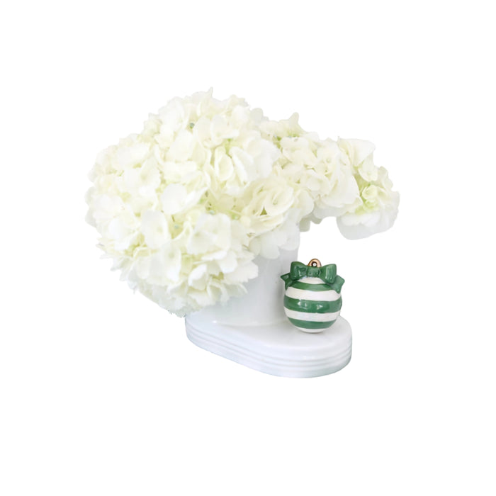 White hydrangeas in a vase on a green and white checkered cloth with a striped ornament.