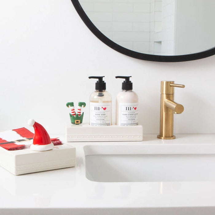 Bathroom counter with two bottles of hand soap, a gold faucet, and festive decor.