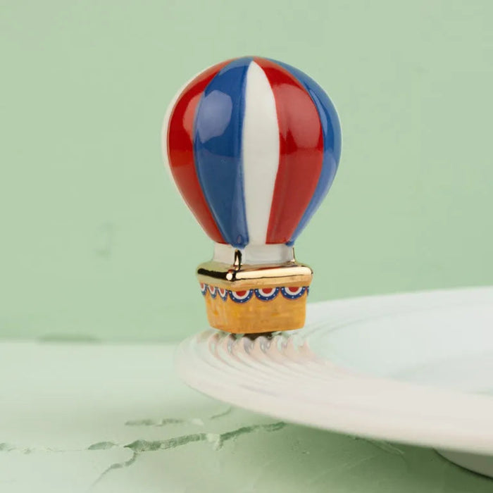 Colorful hot air balloon design on a ceramic plate with a green background
