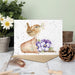 A decorative card displaying a bird resting on a flower pot, with colorful floral accents enhancing the scene.