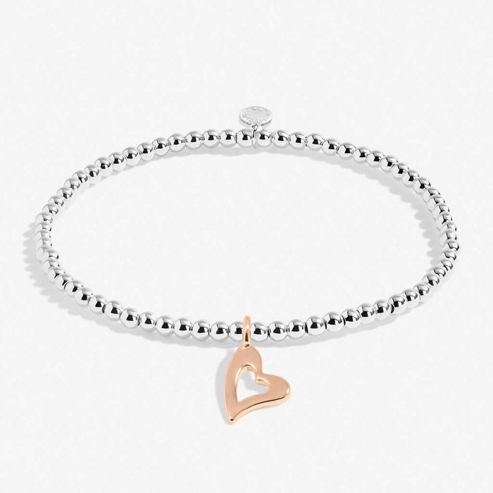 Silver bracelet with a rose gold heart charm on a white background