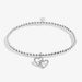 A sleek silver bracelet adorned with a charming heart pendant, perfect for adding a touch of elegance.
