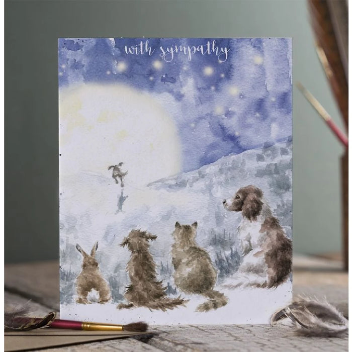 A card depicting four dogs and a cat perched on a hillside, enjoying a sunny day in a serene outdoor setting.