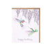 A colorful birthday card featuring a hummingbird surrounded by vibrant flowers and festive decorations.