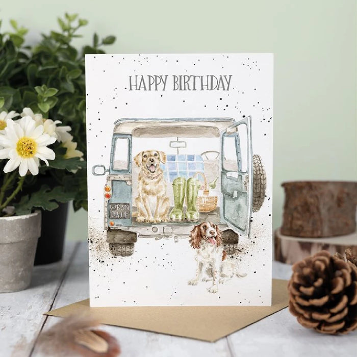  An image of a card showing two dogs in a van's backseat, both appearing curious and happy.