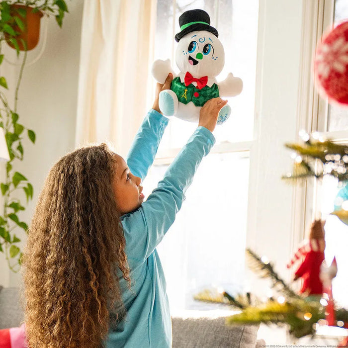 Child holding a plush toy in a room with a Christmas tree and decorations.