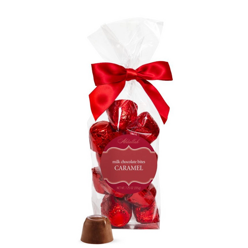 Bag of Abdallah Candies Holiday Caramel Bites wrapped in red foil with a red ribbon, featuring milk chocolate caramels and one unwrapped piece in front.