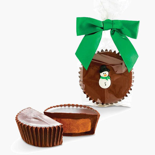 Jumbo chocolate peanut butter cup by Abdallah Candies wrapped with a green bow and decorated with a small snowman, with sliced cup showing creamy peanut butter filling.