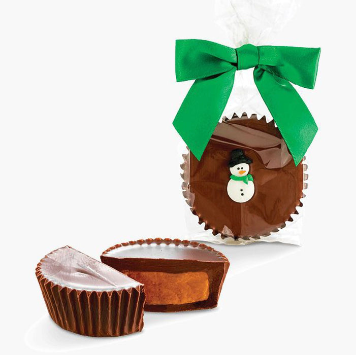 Jumbo chocolate peanut butter cup by Abdallah Candies wrapped with a green bow and decorated with a small snowman, with sliced cup showing creamy peanut butter filling.