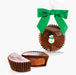 Jumbo chocolate peanut butter cup by Abdallah Candies wrapped with a green bow and decorated with a small snowman, with sliced cup showing creamy peanut butter filling.