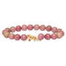 Pink beaded bracelet with a Snow Leopard charm on a white background