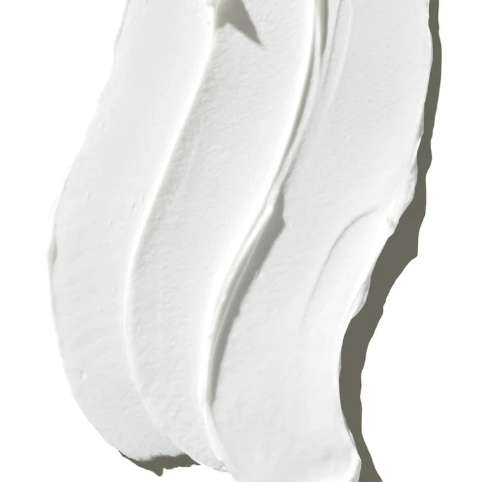 A dollop of white cream placed on a white surface, creating a subtle contrast.