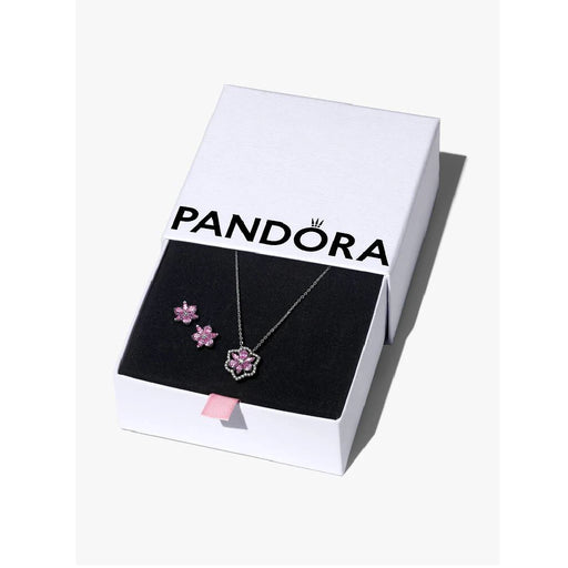 Pandora jewelry set displayed in a box surrounded by delicate pink flowers.