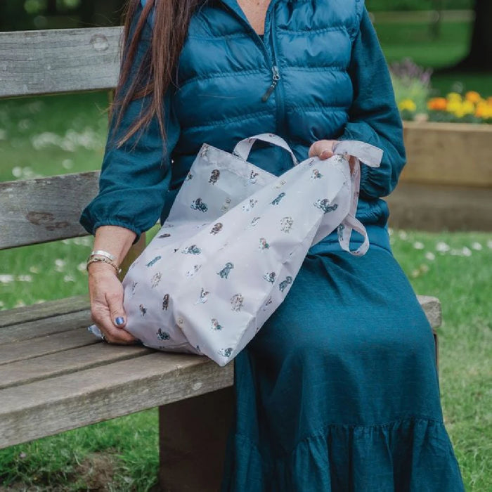 A woman sitting on a bench, holding a bag, appears relaxed in a public park setting.