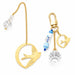 Scout Curated Wears Swallow/Loyalty bookmark and keychain set on a pale pink background. Gold-tone bookmark features a swallow with outstretched wings inside an open circular outline, attached to a long chain with a clear faceted charm