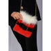 Red fur handbag with white fur top held by a person wearing black clothing.