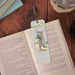 A book with a bookmark resting on it, accompanied by a camera positioned nearby.