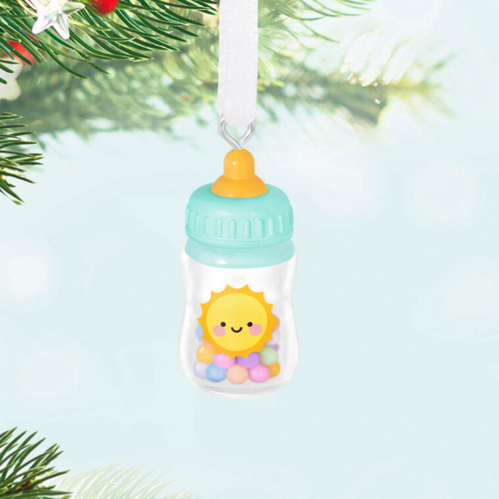 Decorative baby bottle ornament with a sun design hanging on a tree