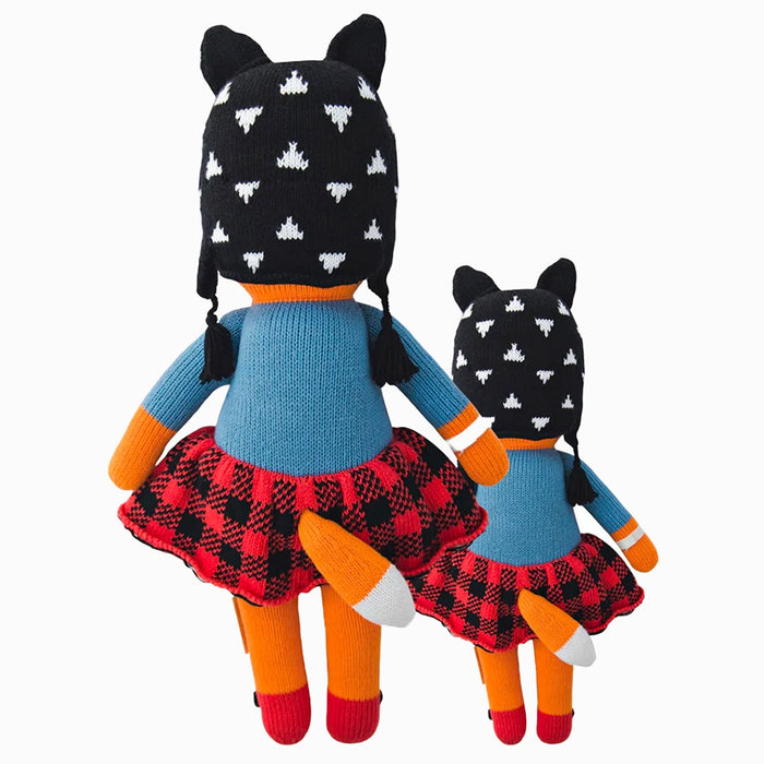 Back view of two Cuddle + Kind Sadie the Fox dolls showing plaid skirts, knit hats, and orange tails