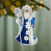 Decorative ornament of a character in a blue outfit with a staff, hanging on a tree branch.
