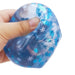 Blue stress ball with snowflake pattern held in a hand on a white background