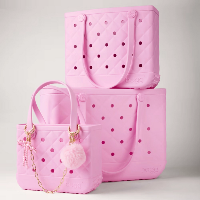 Pink faux fur pouf keychain with gold hardware attached to a quilted Pink Bogg Bag as a stylish bag charm